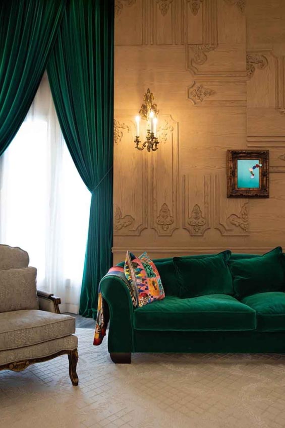 Salon raffiné avec moulures murales, canapé en velours vert et rideaux sur mesure, rénovation réalisée par un architecte d’intérieur en Dordogne.